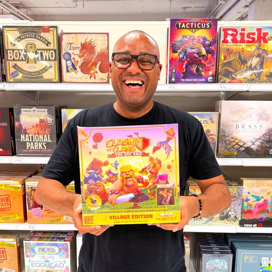 A Maestro Media team member holding the Clash of Clans: The Epic Raid board game in the games aisle at Target.